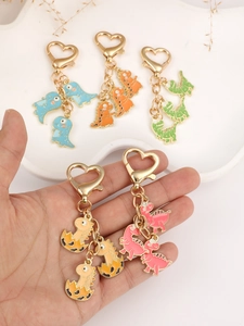 Close-up of cute cartoon dinosaur keychains with colorful enamel finish and gold heart clips