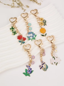 Detail of floral enamel keychains with golden heart clasps and colorful flower designs