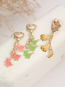 Close-up of cute cartoon dinosaur keychains with heart-shaped clasps on a white bag