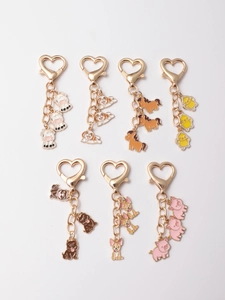 Close-up of enamel animal charms featuring pigs and chicks with gold heart-shaped clasps