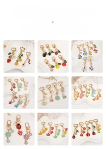 Detail of colorful enamel charms featuring fruits, flowers, and ladybugs on a white tray