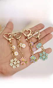 Detailed macro view of colorful enamel flower charms on a gold heart-shaped keychain