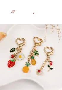 Detailed close-up of fruit and floral gold-plated keychains with enamel charms on display