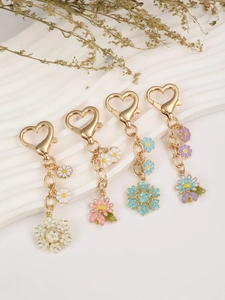 Detail of heart-shaped gold keychains featuring colorful enamel daisy and flower pendants