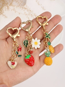 Close-up of strawberry, pineapple and rose charms with gold heart-shaped metal clasps