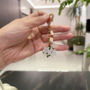 Golden keychain featuring white daisy and lily enamel flowers with large lobster clasp