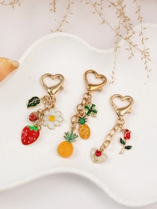 Three-piece set of enamel fruit keychains with strawberry and pineapple in a ceramic tray