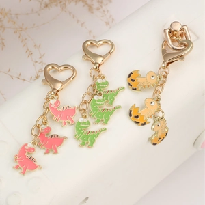 Three cute cartoon dinosaur keychains in pink green and orange with heart lobster clasps