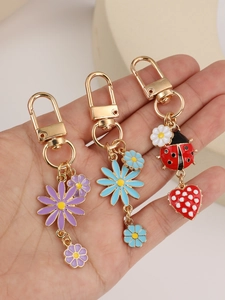 Detail of enamel daisy and ladybug charms with golden lobster clasp held in hand