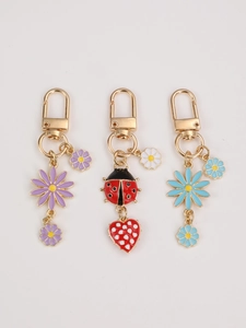 Detail of colorful daisy and ladybug keychains with golden lobster clasps on flat background