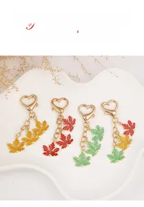 Close-up of colorful maple leaf keychains with gold heart clasps on a white tray