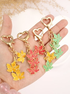 Close-up of four colorful maple leaf keychains with gold heart-shaped spring hooks