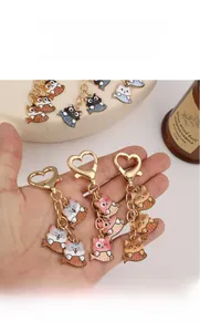 Detailed macro view of cartoon cat fishing keychains with gold heart-shaped lobster clasps