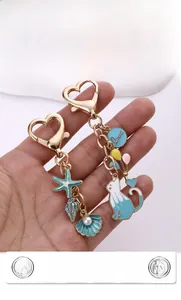Détail de porte-clés chat et étoile de mer en émail bleu avec perles et cœur doré