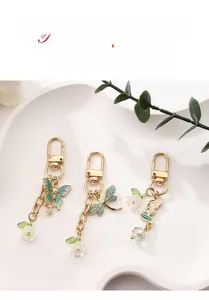 Detailaufnahme der Maiglöckchen- und Schmetterlingsanhänger an goldenen Schlüsselanhängern