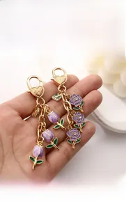 Detailed view of handmade purple tulip and rose flower keychains with gold heart clasp