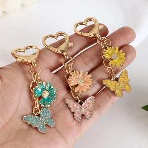 Dreiteiliges Set bunter Schmetterling- und Gänseblümchen-Schlüsselanhänger in der Hand