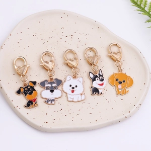 Five assorted cartoon dog alloy keychains with heart hooks on a ceramic tray