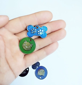 Detail of glitter alloy pet ID tags in bone and round shapes with engraved animal motifs