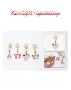 Détail de breloques en émail rose et violet avec abeilles, fleurs et fermoir doré
