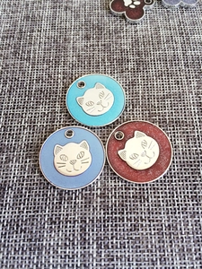 Detailed view of paw-shaped zinc alloy pet ID tags with glitter oil drip and cat embossing