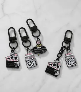 Detail van emaille sleutelhangers in skeletstijl met roos- en plaatontwerp op wit bord