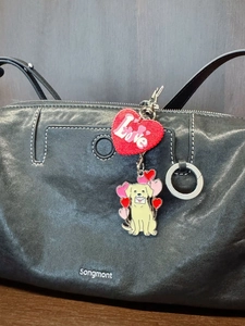 Détail des pendentifs porte-clés en métal Golden Retriever et cœur Love sur un sac en cuir