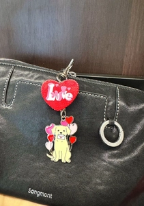 Détail de breloques Golden Retriever et cœur scintillant sur un sac à main en cuir noir