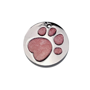 Détail macro d'une médaille ronde en aluminium pour chien avec empreinte de patte rose