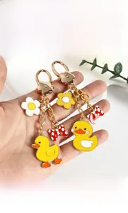 Detail of yellow enamel duck keychain with white daisy and red polka dot bow charms