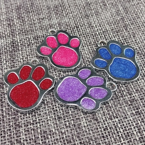 Detailed view of paw-shaped zinc alloy pet ID tags with colorful glitter infill
