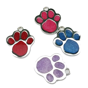 Close-up of glitter paw print pet ID tags in red, pink, blue and purple metal finishes