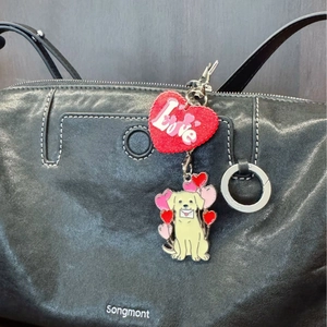 Porte-clés Labrador avec cœur pailleté et ballons sur un sac à main noir en cuir