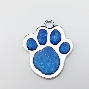 Detail showing blue glitter paw print pet ID tag with silver metal border on white background
