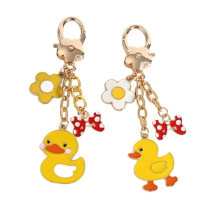 Cute yellow duck keychains with floral charms and red polka dot bows on gold metal