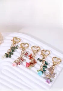 Detail view of five colorful enamel butterfly keychains with heart hooks on a display tray