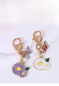 Détails de breloques marguerite et papillon sur porte-clés dorés avec fermoir cœur