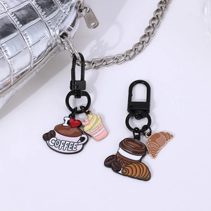 Cute coffee and dessert metal keychains displayed on a stylish silver leather bag