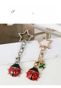 Detail of red ladybug metal keychains with star-shaped rings in gold and silver finishes