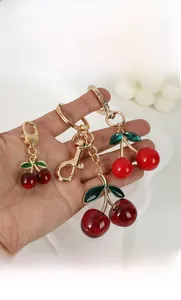 Détail des bijoux de sac cerise avec feuilles en émail vert et fermoirs en cœur dorés