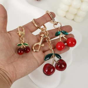 Trois porte-clés cerise en résine brillante et métal doré pour sacs et voitures