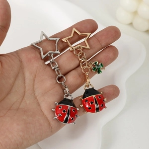 Creative metal ladybug keychains in gold and silver with star-shaped rings in hand