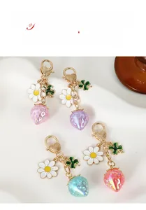 Detail of strawberry keychains with pearl texture flowers and gold heart clasp