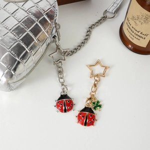 Creative ladybug keychain with star-shaped ring on a silver textured handbag