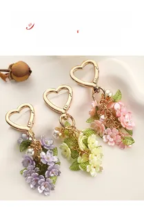 Close-up of floral keychain with gradient petals, pearls and heart-shaped metal clasp