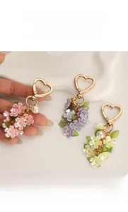 Detail shot of heart-shaped gold clasps with resin flowers and pearls on floral keychains