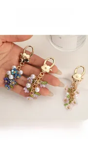 Close-up of colorful resin flower and pearl charms on a golden metal keychain link