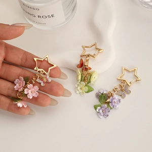Star-shaped keychain with colorful flower and butterfly charms on ceramic tray