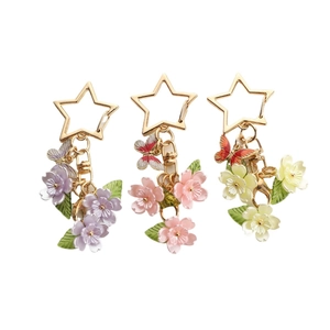 Star-shaped keychain with colorful cherry blossom and butterfly charms in three pastel colors