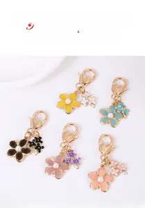 Détail de cinq porte-clés fleurs de cerisier colorés avec crochets cœur et perles
